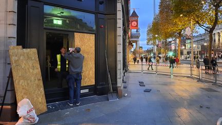 Magasin Asics dont les vitrines cassées sont remplacees par des panneaux de bois. (RICHARD PLACE / RADIOFRANCE)