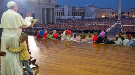 Un petit gar&ccedil;on enlace le pape Fran&ccedil;ois lors d'une allocution sur la place Saint Pierre (Vatican), le 26 octobre 2013. (OSSERVATORE ROMANO / AFP)