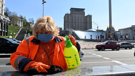 Une employée municipale nettoie et désinfecte une entrée de métro, place de l'Indépendance à Kiev (Ukraine), le 7 avril 2020.&nbsp; (SERGEI SUPINSKY / AFP)