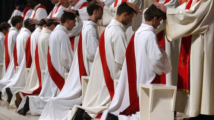 Onze nouveaux pr&ecirc;tres sont agenouill&eacute;s lors d'une messe d'ordination, le 26 juin 2004, &agrave; la cath&eacute;drale Notre-Dame de Paris. (PIERRE ANDRIEU / AFP)