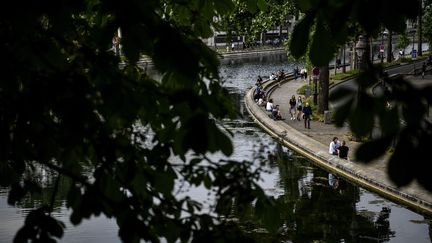 Des personnes assises et marchant le long le du canal Saint-Martin, à Paris, le 8 mai 2020. (CHRISTOPHE ARCHAMBAULT / AFP)