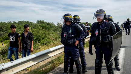 Des CRS facent &agrave; des migrants, le 5 ao&ucirc;t 2015 sur la route vers le port de Calais (Pas-de-Calais). (PHILIPPE HUGUEN / AFP)