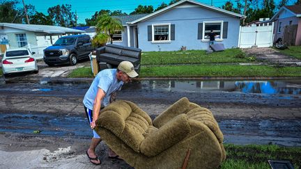 A man moves a chair on October 11, 2024 in Tampa, Florida (United States), as residents clear the streets after Hurricane Milton. (GIORGIO VIERA / AFP)