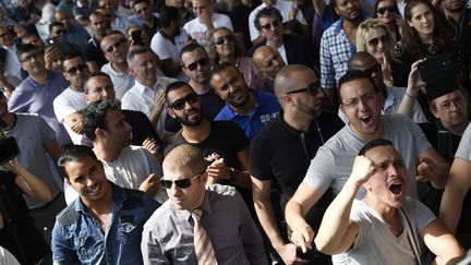 Des chauffeurs de taxi &eacute;coutent le pr&eacute;sident de la F&eacute;d&eacute;ration des taxis ind&eacute;pendants annoncer la tenue d'une r&eacute;union au minist&egrave;re de l'Int&eacute;rieur, jeudi 25 juin 2015, alors qu'ils manifestent porte Maillot &agrave; Paris. (LOIC VENANCE / AFP)