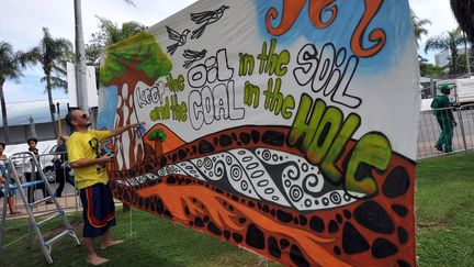 Un artiste sud-africain expose une banderole &agrave; l'ext&eacute;rieur du site qui accueille la conf&eacute;rence de Durban (Afrique du Sud), le 30 novembre 2011. (ALEXANDER JOE / AFP)