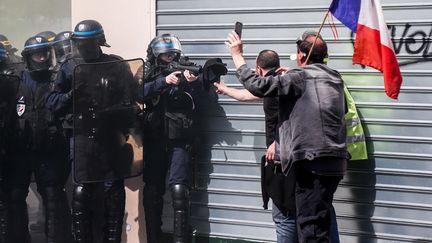 Un policier pointe un lanceur de balles de défense (LBD) vers des manifestants lors d'une manifestation des "gilets jaunes'', le 20 avril 2019 à Paris. (ZAKARIA ABDELKAFI / AFP)