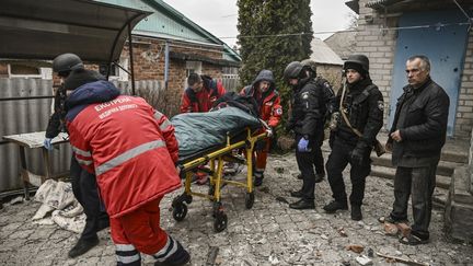 Des ambulanciers évacuent un homme lourdement blessé après une attaque à la bombe à fragmentation à Kramatorsk, dans l'est de l'Ukraine, le 18 mars 2023. (ARIS MESSINIS / AFP)