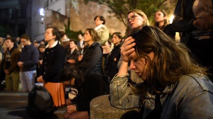 A 20h, ils sont déjà des dizaines à se rassembler sur la place Saint-Michel, au plus près de la cathédrale, pour voir ce qu'il se passe et se recueillir. Des chants chrétiens résonnent. Les riverains ont eux été évacués, par mesure de sécurité.&nbsp; (ERIC FEFERBERG / AFP)