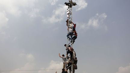 Des supporters afghans c&eacute;l&egrave;brent, accroch&eacute;s &agrave; un poteau &eacute;lectrique, la victoire de leur &eacute;quipe face &agrave; l'Inde en finale du championnat d'Asie du Sud de football &agrave; Kaboul (Afghanistan), le 12 septembre 2013. (MOHAMMAD ISMAIL / REUTERS)