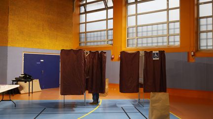 Un électeur glisse son bulletin dans une enveloppe dans un bureau de vote du 9e arrondissement de Paris, le 10 avril 2022, lors du premier tour de la présidentielle. (MAXPPP)