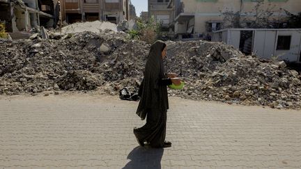 Une femme marche dans les décombres de Gaza, le 21 octobre 2024. (MOIZ SALHI / MIDDLE EAST IMAGES / AFP)