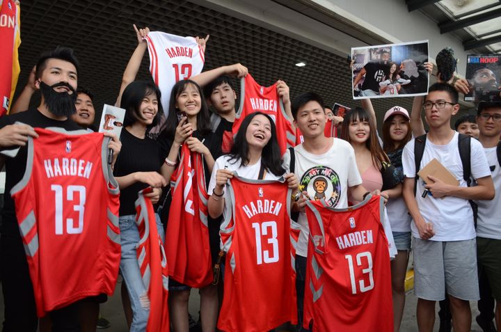 Des fans chinoise des Houston Rockets brandissent des maillots de James Harden à l'aéroport international de Shangai (Chine), le 29 juin 2018. (ZHONG FUBAO / IMAGINECHINA / AFP)