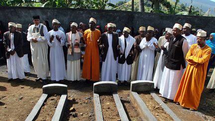 Des proches des victimes du crash de la Yemenia prient devant leurs tombes, le 30 juin 2010 &agrave; Moroni (Comores), un an jour pour jour apr&egrave;s le drame. (YUSUF IBRAHIM / AFP)