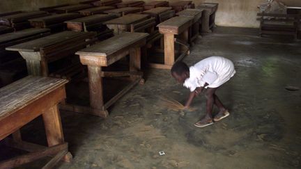 Une fillette balaie une salle de classe, le 19 septembre 2001, dans le village de N'Zikro, situé à quelques kilomètres à l'ouest d'Abidjan, la capitale économique de la Côte d'Ivoire.&nbsp; (GEORGES GOBET / AFP)