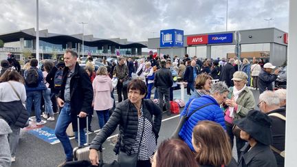 Des passagers patientent devant l'aéroport de Bordeaux-Mérignac (Gironde) après une fausse alerte à la bombe, le 18 octobre 2023. (SEVERINE DABADIE / AFP)