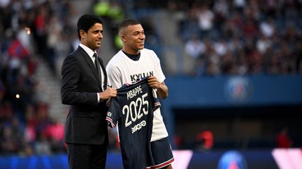 Kylian Mbappé pose avec Nasser Al-Khelaifi pour officialiser son nouveau contrat&nbsp;avec le PSG, le&nbsp;21 mai 2022, au Parc des Princes.&nbsp; (ANNE-CHRISTINE POUJOULAT / AFP)