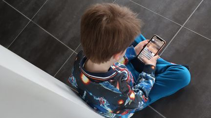 Un enfant avec un téléphone portable dans les mains. (VANESSA MEYER / L'ALSACE / MAXPPP)