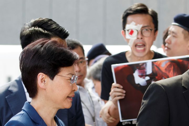 La cheffe du pouvoir exécutif de Hong Kong, Carrie Lam, passe devant des manifestants, devant son bureau, à Hong Kong, le 13 août 2019. (THOMAS PETER / REUTERS)