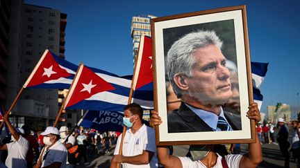 Une femme brandit un portrait du président cubain Miguel&nbsp;Diaz-Canel lors d'un meeting à La Havane le 17 juillet 2021. (YAMIL LAGE / AFP)