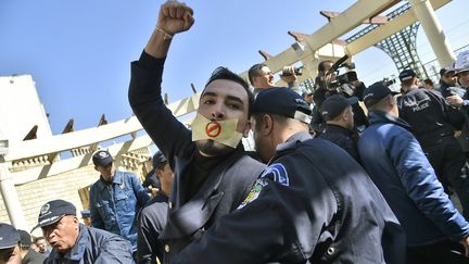 Un policier interpelle un manifestant lors d'un rassemblement de journalistes protestant contre la couverture médiatique du mouvement de contestation contre une nouvelle candidature d'Abdelaziz Bouteflika, le 28 février 2019 à Alger (Algérie).&nbsp; (RYAD KRAMDI / AFP)