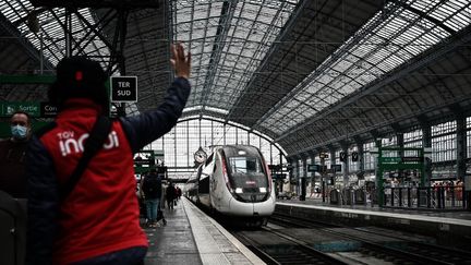 Un membre du personnel de la SNCF lance un signal à un TGV à la gare de Bordeaux. (PHILIPPE LOPEZ / AFP)