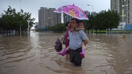 Un homme portant une petite fille traverse une rue inond&eacute;e &agrave; Shenzhen (Chine), le 11 mai 2014. (REUTERS)