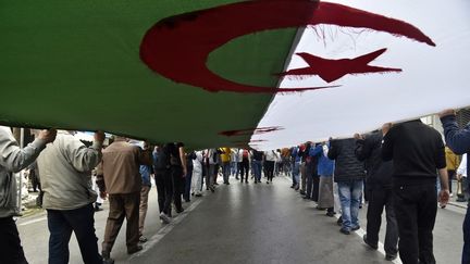 Des Algériens déploient un drapeau national géant lors d’une manifestation anti-gouvernementale&nbsp;à Alger, le 2 avril 2021. (RYAD KRAMDI / AFP)