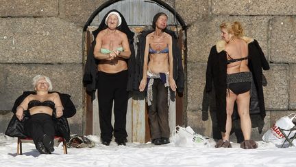 Des femmes prennent un bain de soleil contre un mur de la&nbsp;forteresse Pierre-et-Paul &agrave; Saint-Petersbourg (Russie), le 10 mars 2013. (ALEXANDER DEMIANCHUK / REUTERS)