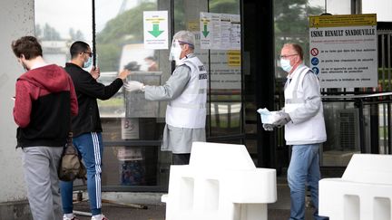 Une distribution de masques sanitaires contre le Covid-19 devant l'usine Renault de Sandouville, en mai 2020. Le site rouvrait alors après la fin du premier confinement. (LOU BENOIST / AFP)