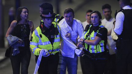 Des policiers escortent un passant, alors qu'ils sécurisent la scène de l'attaque terroriste qui a frappé Londres (Royaume-Uni), le 3 juin 2017. (DANIEL SORABJI / AFP)