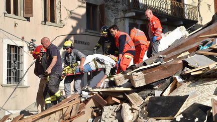 Les secours portent un homme sorti des décombres le 24 août à Amatrice en Italie (STR / AFP)