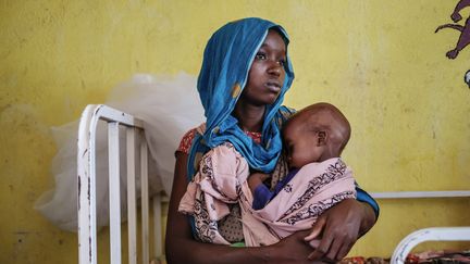 Une femme tient un enfant souffrant de malnutrition dans le centre de santé de Kelafo (Éthiopie). (EDUARDO SOTERAS / AFP)