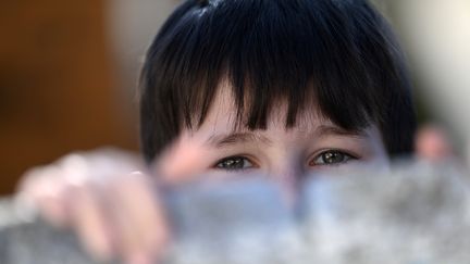 A refugee boy looks at a barrier at the refugee shelter, where around 150 Roma and Ukrainians currently live, in Uzhhorod, western Ukraine, March 2, 2023. (ATTILA KISBENEDEK / AFP)