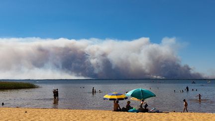 Depuis la plage du lac de Sanguinet (Gironde), le nuage de fumée de l'incendie en cours au pied de la dune du Pilat, le 12 juillet 2022. (JEROME GILLES / NURPHOTO / AFP)