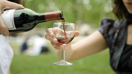 Une bouteille de vin est versée dans un verre lors d'un pique-nique. (MAXPPP)