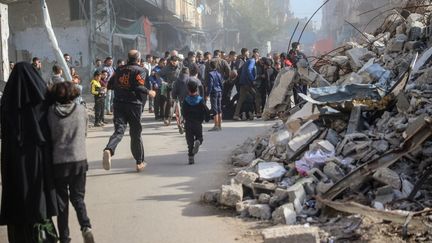 Des passants se précipitent vers les lieux d'une frappe israélienne dans le camp de réfugié de Bureij, dans la bande de Gaza, le 22 décembre 2024. (EYAD BABA / AFP)