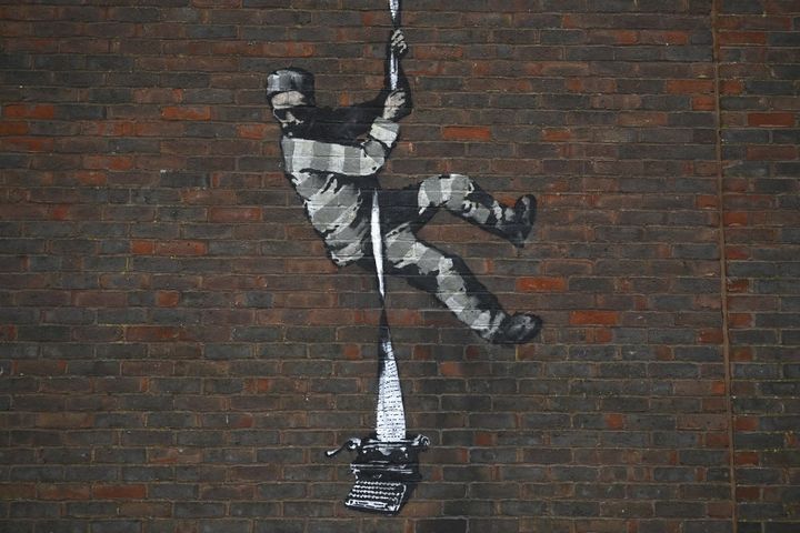 Graffiti du street artist britannique Banksy peint le 4 mars 2020 sur le mur de la prison de Reading, où fut incarcéré Oscar Wilde, de 1895 à 1897, pour homosexualité. (BEN STANSALL / AFP)