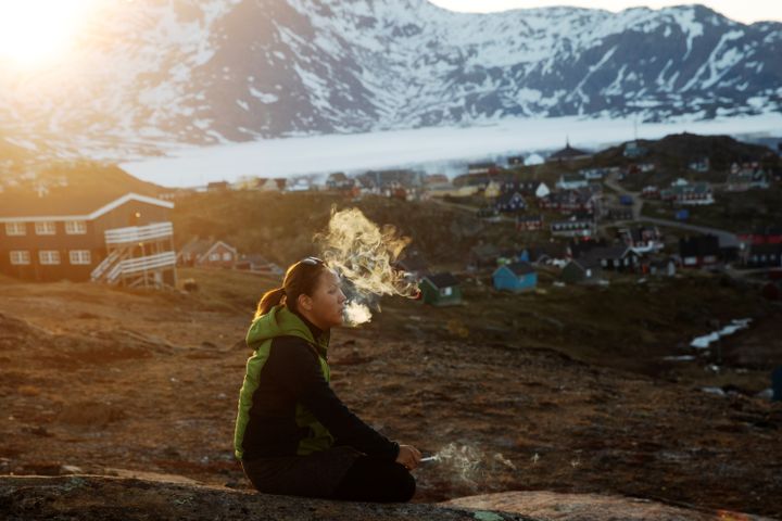 Une jeune femme fume une cigarette aux abords de la ville de Tasiilaq, au Groenland, à l'avant-poste du réchauffement climatique, le 18 juin 2018.&nbsp; (LUCAS JACKSON / REUTERS)