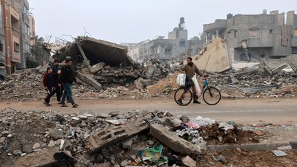 Des passants dans une rue de Rafah, dans le sud de la bande de Gaza, dont les bâtiments ont été détruits par un bombardement israélien, en février 2024. (MOHAMMED ABED / AFP)