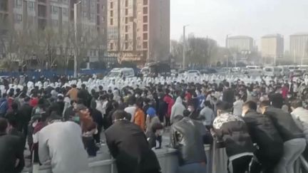 Une photo transmise à l'agence Associated Press, le 23 novembre 2022, montrant&nbsp;des ouvriers de l'usine d'iPhone de Foxconn à Zhengzhou,&nbsp;en Chine, face à la police antiémeute. (AP)