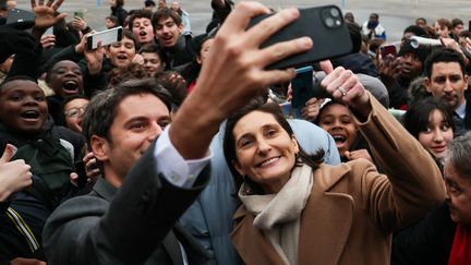 Le premier ministre Gabriel Attal et la ministre de l'Education nationale, des Sports et des Jeux olympiques et paralympiques Amélie Oudéa-Castéra, prennent un selfie avec des élèves, lors d'une visite au collège Saint-Exupéry, à Andrésy (Yvelines), le 12 janvier 2024. (ALAIN JOCARD / AFP)