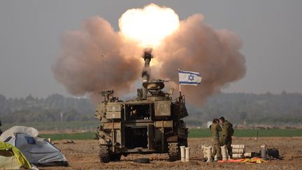 Des soldats israéliens tirent un obus en direction de la bande de Gaza, le 12 décembre 2023, à la frontière entre Israël et l'enclave palestinienne. (JACK GUEZ / AFP)