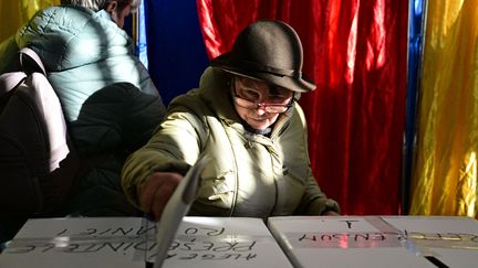 Une femme vote pour le premier tour de l'élection présidentielle en Roumanie, dans un bureau de Bucarest, le 24 novembre 2024. (DANIEL MIHAILESCU / AFP)