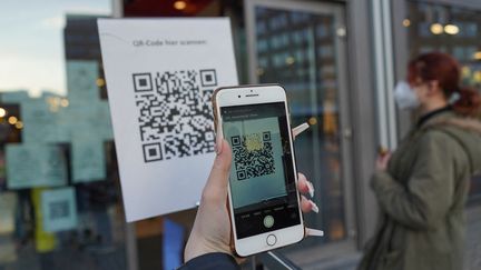 Un téléphone scanne un QR code à l'entrée d'un magasin de Berlin (Allemagne), le 9 mars 2021. (JORG CARSTENSEN / AFP)