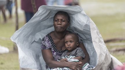 Une femme et un enfant se protègent&nbsp;contre les intempéries, le 17 août 2021 près des Cayes, quelques jours après le séisme qui a frappé Haïti. (REGINALD LOUISSAINT JR / AFP)