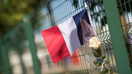  (Une rose et un drapeau déposés sur le grillage de l'usine Air Products à St Quentin-Fallavier en hommage à Hervé Cornara, 54 ans, mort décapité dans l'attentat islamiste qui a frappé la France vendredi © Maxppp)