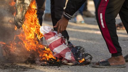 Le drapeau américain brûlé par des Irakiens durant une manifestation, le 30 décembre 2019 à Basra (Irak). (HUSSEIN FALEH / AFP)