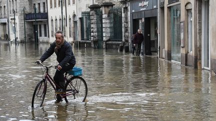 Un cycliste dans une rue inondée de Ornans, dans le Doubs, le 23 janvier 2018. (SEBASTIEN BOZON / AFP)