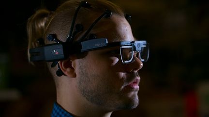 Un casque EEG posé sur la tête d'un homme qui regarde un écran à Toronto (Canada). (CHRIS SO / TORONTO STAR / GETTYIMAGES)