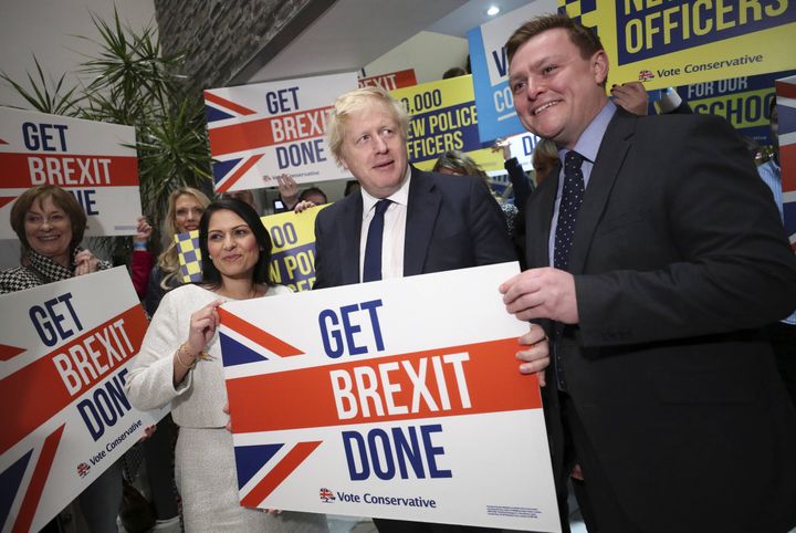 Priti Patel et Boris Johnson portent une affiche pour l'application du Brexit, à Colchester en Angleterre, le 2 décembre 2019. (HANNAH MCKAY / AP / SIPA)